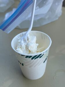 A paper cup filled with vanilla ice cream.